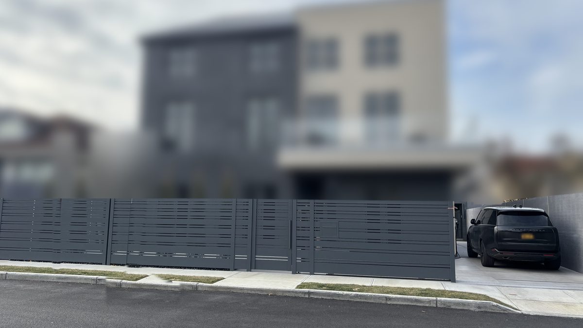 Gray horizontal slat fence and gate in front of a modern house